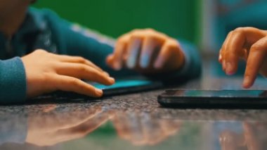 İnsanlarla bir Cafe masada oturan telefon ile oynayan çocuk.