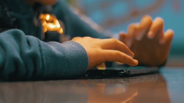 Niño jugando con el teléfono móvil en la mesa — Vídeo de stock