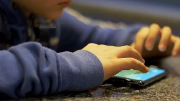 Enfant jouant avec un téléphone portable sur la table — Video