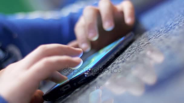 Niño jugando con el teléfono móvil en la mesa — Vídeo de stock