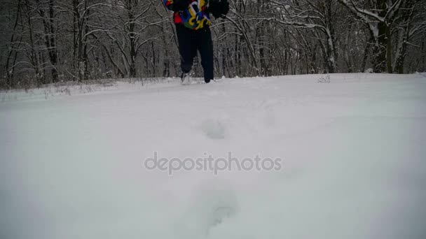 Людина, що біжить в глибокий сніг в зимовому лісі на сніжний день. Повільний рух — стокове відео