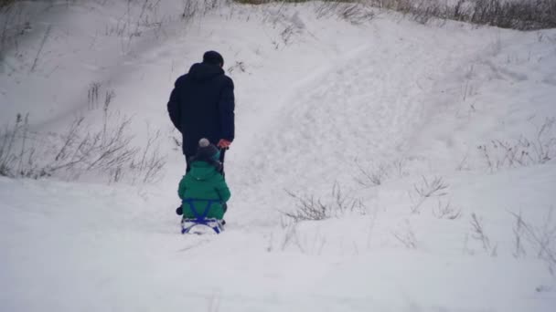 Mann zieht Tochter beim Rodeln im Winterwald