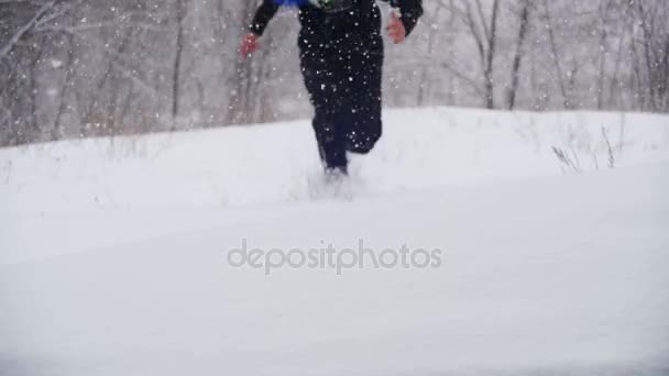 Šťastný člověk ponoří do hlubokého sněhu a baví v zimě borovým lesem. Zpomalený pohyb — Stock video