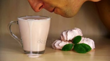 Adam ağız ve dil içme yoğurt bir ahşap zemin üzerine saydam bir cam. Ağır çekim