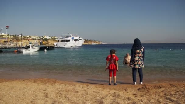 Muslim woman wearing a hijab with baby on the shore of the Red Sea beach. — Stock Video