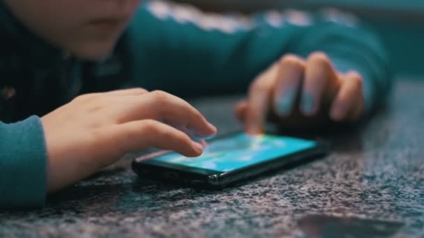 Manos del niño jugando con el teléfono móvil en la mesa — Vídeo de stock