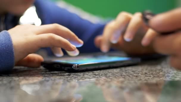 Niño jugando con el teléfono móvil en la mesa — Vídeos de Stock