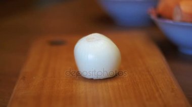 Ev mutfakta bir kesme tahtası üzerinde iki parçaya bıçakla kesme soğan. Ağır çekim