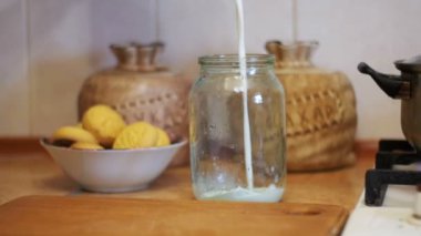 Süt şeffaf bir kavanoz bir arka plan, eve mutfak dökülür. Ağır çekim