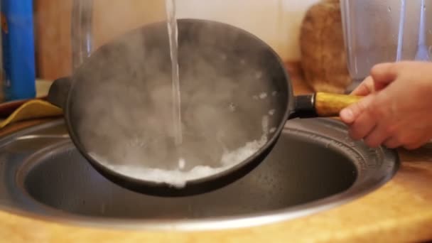 Donna lava una padella calda sotto l'acqua corrente in una cucina di casa. Rallentatore — Video Stock