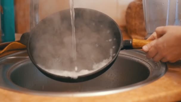 Donna lava una padella calda sotto l'acqua corrente in una cucina domestica. Rallentatore — Video Stock