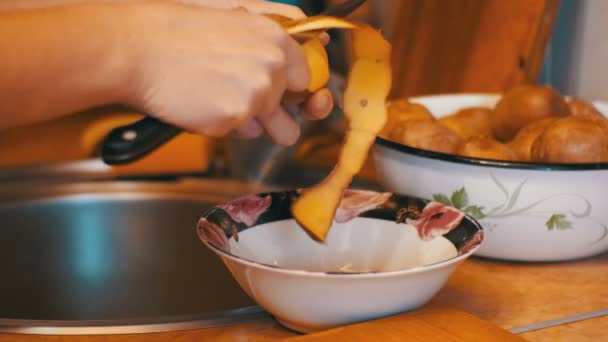 Чистка картошки на домашней кухне — стоковое видео