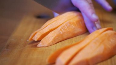 Bir bıçak ile kadın el Ahşap mutfak tahtası ev bir mutfak bıçağı ile havuç dilimleri