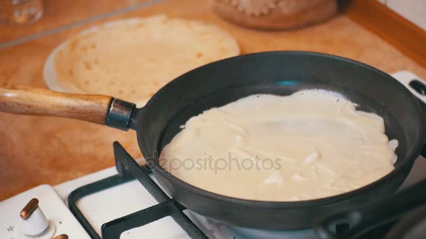 Виготовлення млинців з тіста, плоскі тістечка на гарячій сковороді на домашній кухні — стокове відео