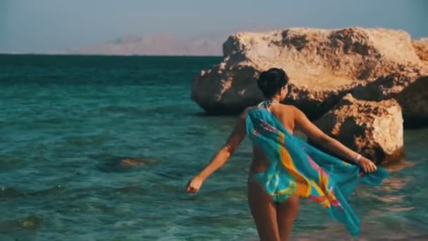 Glad tjej med halsduk promenader på sommaren stranden i Röda havet. Slow Motion — Stockvideo