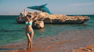 Mutlu kız Red Sea'deki/daki yaz sahilde yürüyüş eşarp ile. Ağır çekim