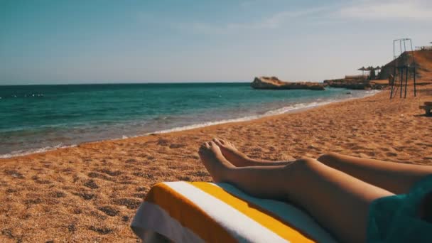 Piernas de mujer acostada en la playa Sun Lounger cerca del Mar Rojo, Egipto — Vídeos de Stock