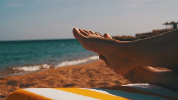 Ноги жінка лежить на пляжі шезлонг біля моря — стокове відео