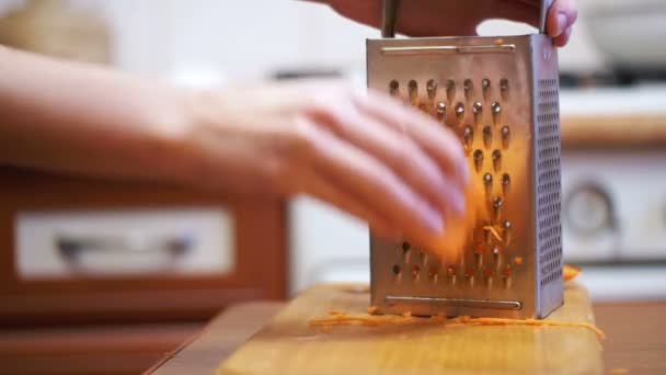 Χέρια γυναίκα τρίβει τα καρότα στον τρίφτη σε μια κουζίνα στο σπίτι. Αργή κίνηση — Αρχείο Βίντεο