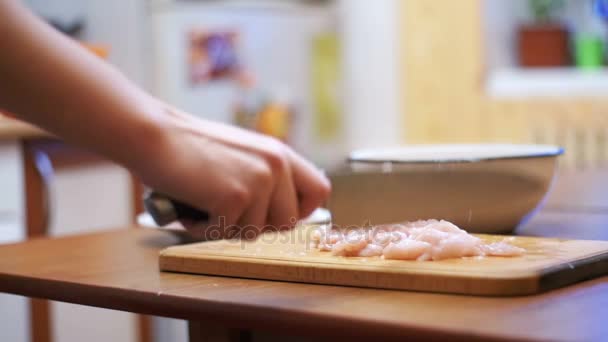 Handen van de vrouw met een mes gesneden vlees op een houten snijplank in de eigen keuken. Slow Motion — Stockvideo