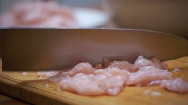 Mains de femme avec un couteau de coupe de viande sur une planche à découper en bois dans la cuisine de la maison. Mouvement lent — Video