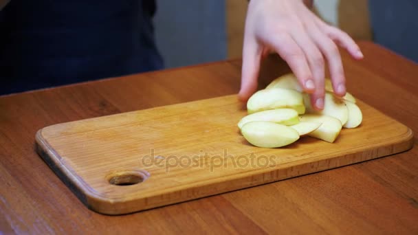 Mãos de mulher com uma faca em fatias de maçã em uma placa de cozinha de madeira em uma cozinha doméstica — Vídeo de Stock