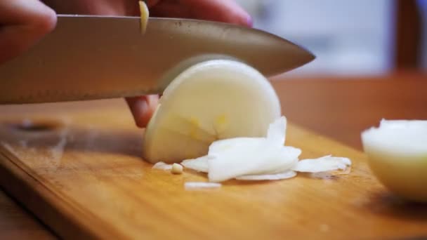 Vrouw Chef gesneden uien op een houten snijplank in een huis keuken — Stockvideo