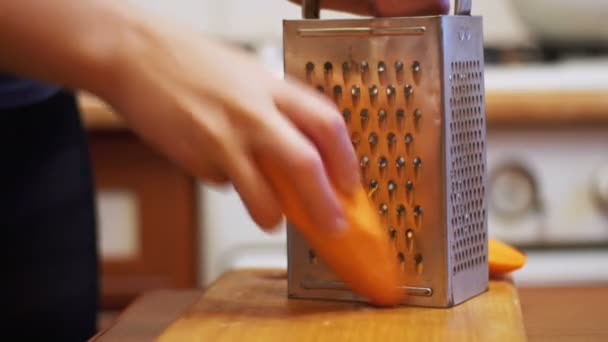 Las manos de la mujer frotando zanahorias en el rallador en una cocina casera — Vídeos de Stock