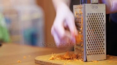 Kadın eller üzerinde bir ev mutfak rende havuç sürtünme. Ağır çekim