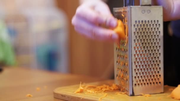 Mãos de mulher esfregando cenouras no ralador em uma cozinha doméstica. Movimento lento — Vídeo de Stock