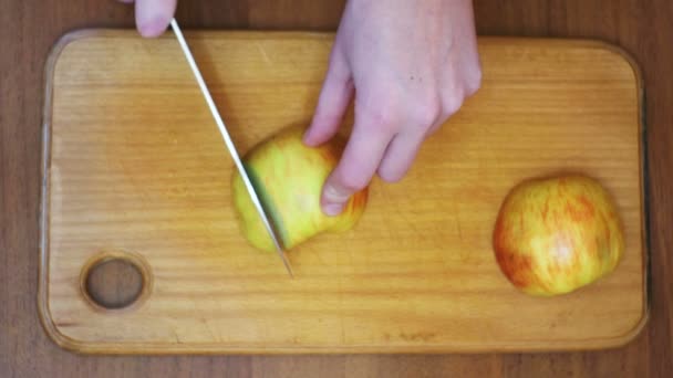 Женщина ручки с ножом нарезанный яблоко на деревянной кухонной доске в домашней кухне — стоковое видео