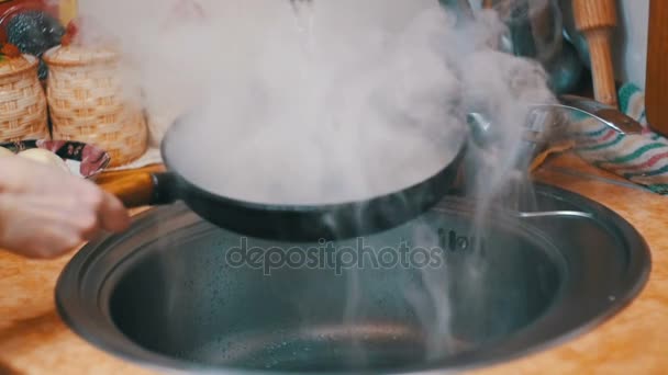 Eine heiße Pfanne verwandelt einen Strahl kalten Wassers in einer Spüle der heimischen Küche in Dampf. Zeitlupe — Stockvideo