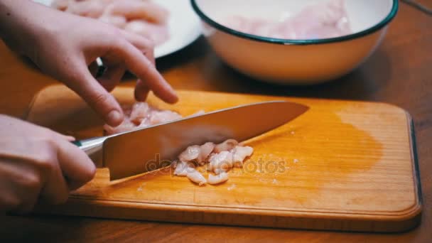 Женские руки с ножом нарезанное мясо на деревянной доске для резки в домашней кухне. Slow Motion — стоковое видео