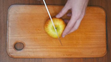 Ev bir mutfak ahşap mutfak tahtası Apple kadın elinde bir bıçakla dilimlenmiş