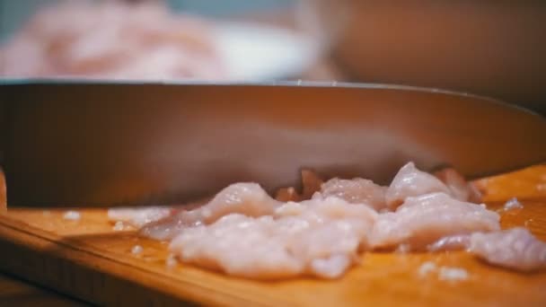 Mãos de mulher com uma faca de carne fatiada em uma placa de corte de madeira na cozinha doméstica. Movimento lento — Vídeo de Stock