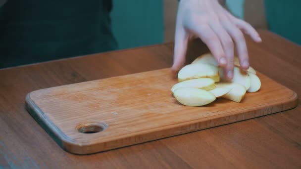 Женщина ручки с ножом нарезанный яблоко на деревянной кухонной доске в домашней кухне — стоковое видео