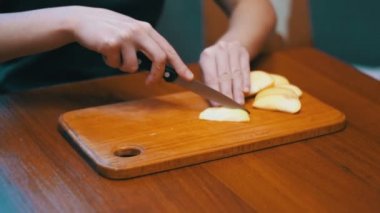 Kadın elinde bir bıçakla bir ev mutfak ahşap mutfak tahtası Apple dilimlenmiş. Ağır çekim