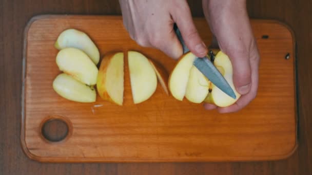 Manos de mujer con un cuchillo en rodajas de manzana en un tablero de cocina de madera en una cocina casera — Vídeos de Stock