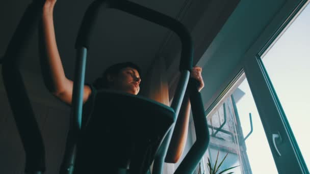 Silhouette della ragazza che esercita sul Cardio Trainer Cross Trainer a casa contro la finestra . — Video Stock