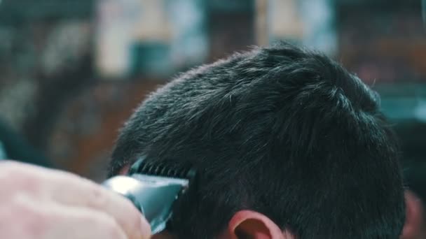 Haarschneider schneidet jungen Mann mit Haarschneidemaschine — Stockvideo