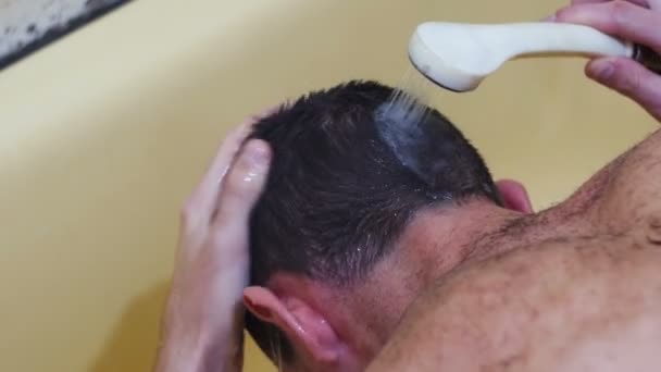 Jeune homme se lave la tête sous la douche . — Video