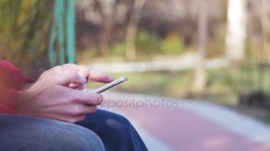 Genç şehir parkta bir bankta bir cep telefonu kullanan adam