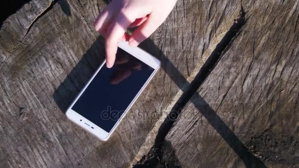 Finger gesta dívka spravuje Smartphone na dřevěné pozadí — Stock video