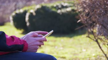 Genç şehir parkta bir bankta bir cep telefonu kullanan adam