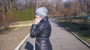 Gülümseyen ve yavaş şehir parkında bir smartphone cep telefonu ile konuşurken mutlu genç kız