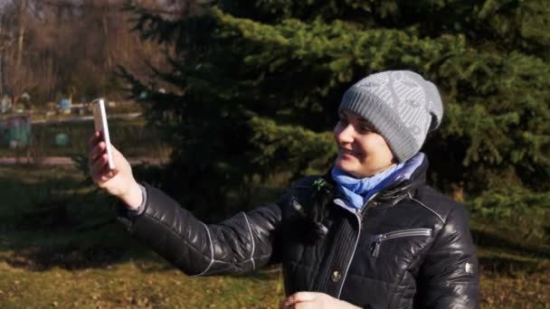 Glückliches junges Mädchen beim Selfie mit ihrem Smartphone im Frühling in einem Stadtpark. — Stockvideo