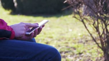 Genç şehir parkta bir bankta bir cep telefonu kullanan adam