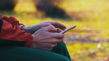 Genç şehir parkta bir bankta bir cep telefonu kullanan adam