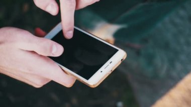 Kent parkta bir bankta bir akıllı telefon kullanan genç adam