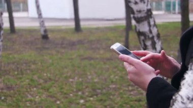 Genç şehir parkında bir akıllı telefon kullanan kadın
